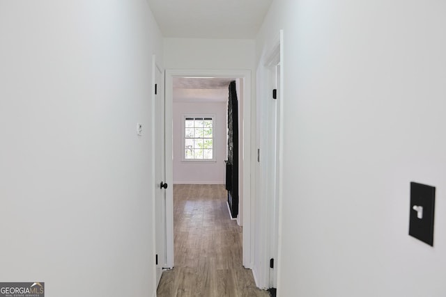 hall with baseboards and light wood finished floors