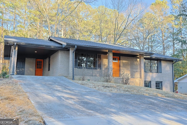 view of front of house with a carport, brick siding, driveway, and a porch