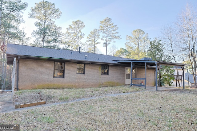 rear view of house featuring a shingled roof and brick siding