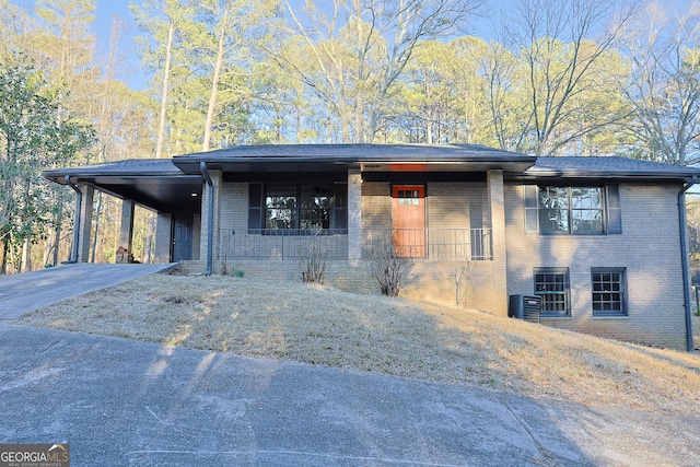 view of front facade with a carport, brick siding, concrete driveway, and cooling unit