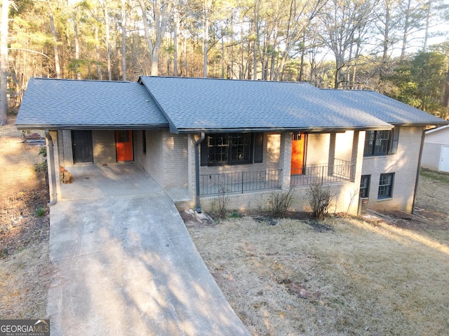 ranch-style home featuring a porch, an attached carport, brick siding, and roof with shingles