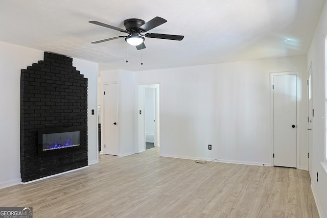 unfurnished living room featuring light wood finished floors, a brick fireplace, and baseboards