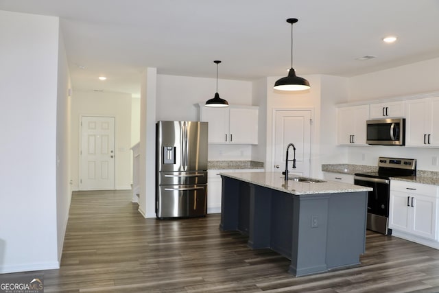 kitchen with a center island with sink, appliances with stainless steel finishes, white cabinetry, pendant lighting, and a sink