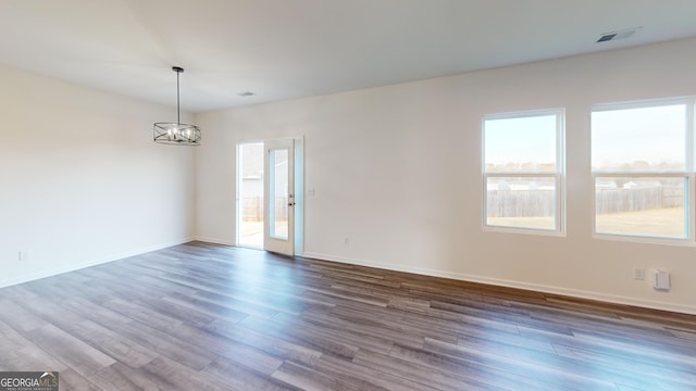 empty room featuring baseboards, dark wood-type flooring, visible vents, and an inviting chandelier