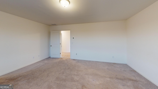 empty room with light colored carpet, visible vents, and baseboards