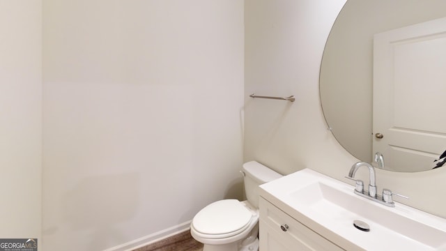 bathroom featuring baseboards, vanity, toilet, and wood finished floors