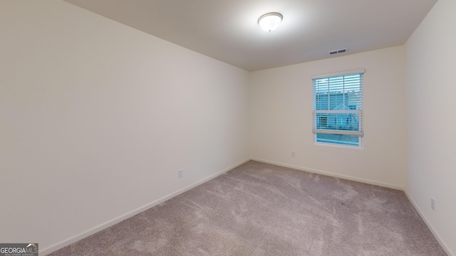 empty room featuring light carpet, baseboards, and visible vents