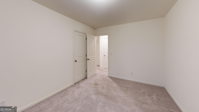 spare room with light colored carpet and baseboards