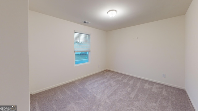 spare room with light carpet, visible vents, and baseboards