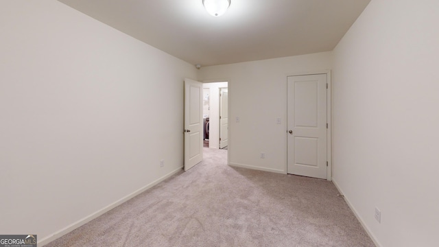 empty room featuring light carpet and baseboards