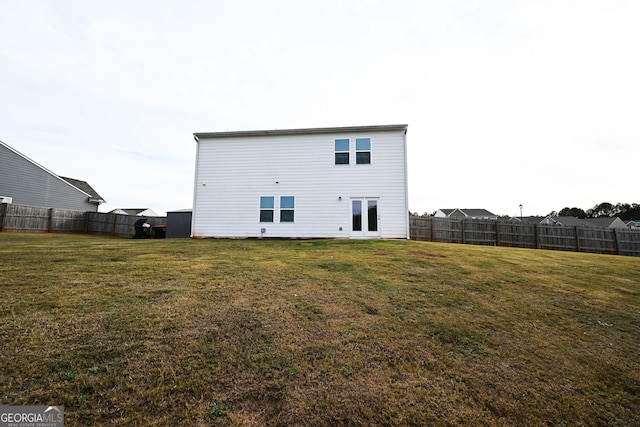 rear view of house featuring a fenced backyard and a yard