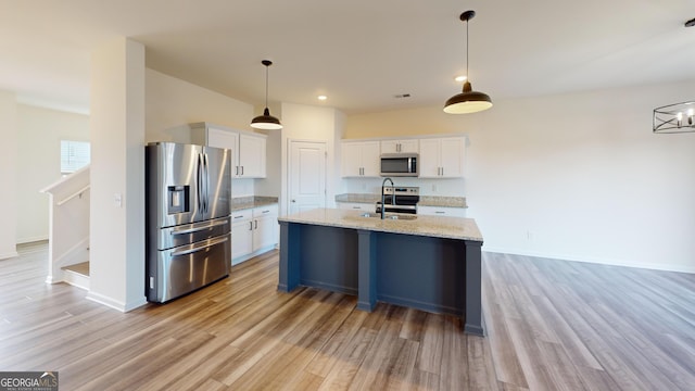 kitchen with appliances with stainless steel finishes, light stone counters, light wood-style floors, white cabinetry, and a sink