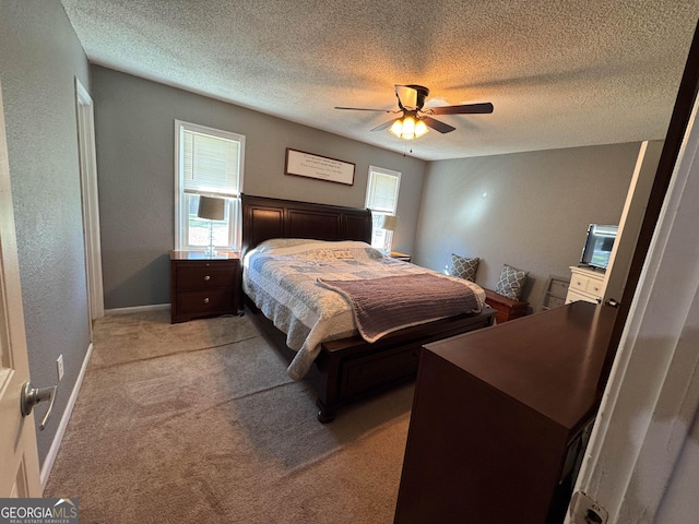 bedroom with ceiling fan, light carpet, and a textured ceiling