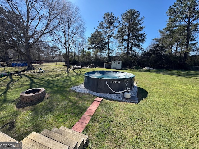 view of yard with an outbuilding, a covered pool, an outdoor fire pit, and a shed