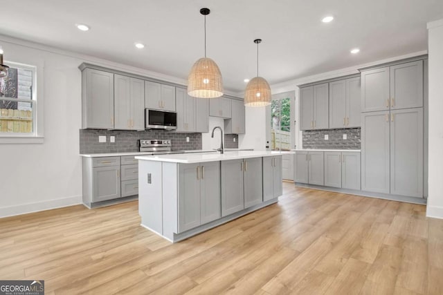 kitchen featuring gray cabinetry, stainless steel appliances, and decorative light fixtures