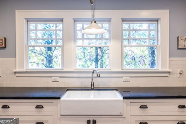 kitchen featuring white cabinets, pendant lighting, sink, and backsplash