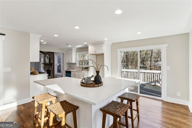 kitchen featuring white cabinetry, a kitchen bar, a wealth of natural light, and hardwood / wood-style floors