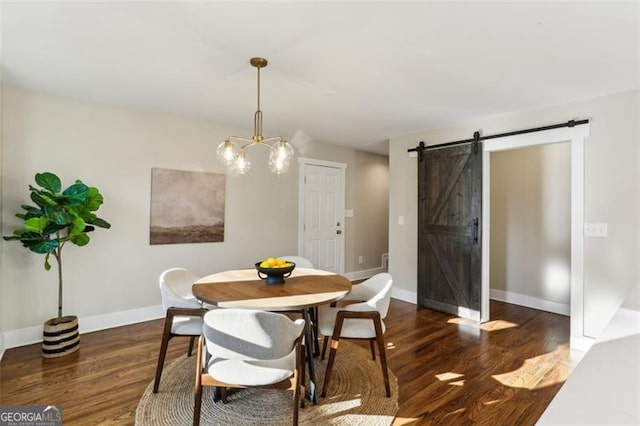 dining area featuring dark hardwood / wood-style flooring, a barn door, and a notable chandelier