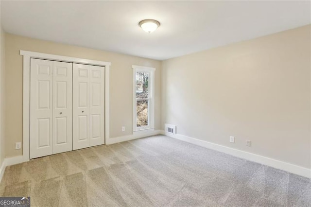 unfurnished bedroom featuring a closet and light colored carpet