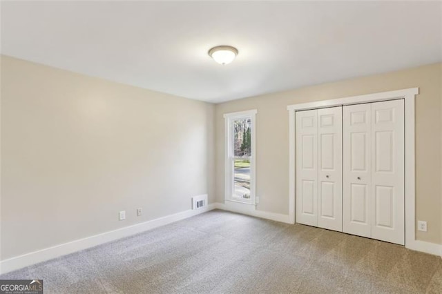 unfurnished bedroom featuring a closet and light colored carpet