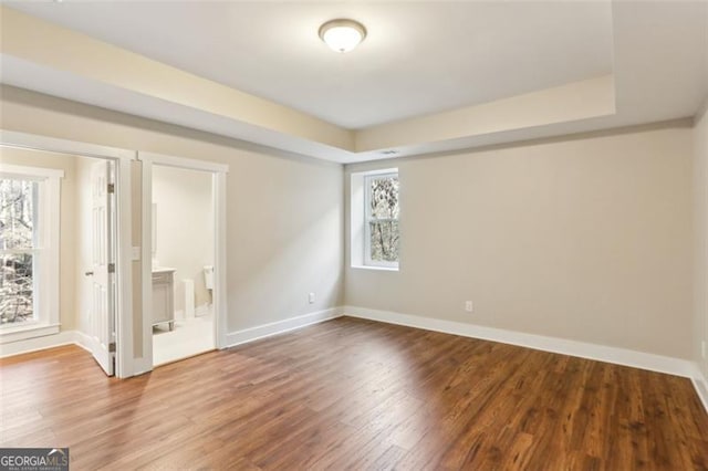 empty room featuring a tray ceiling and hardwood / wood-style floors