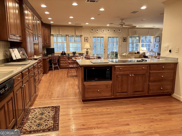 kitchen featuring visible vents, light wood-style floors, a peninsula, black appliances, and recessed lighting