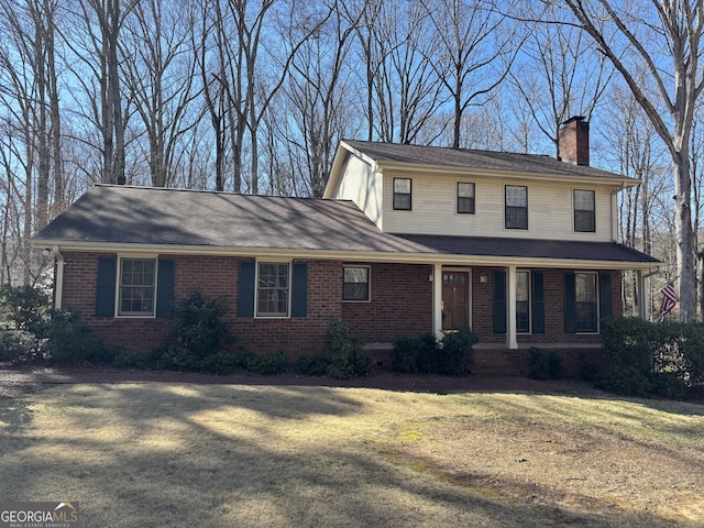 view of front of house featuring a chimney, a front lawn, and brick siding