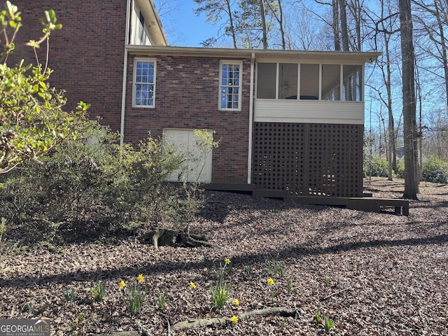 view of side of home featuring brick siding and a sunroom