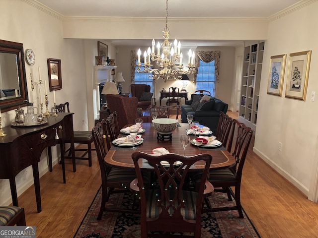 dining space featuring baseboards, ornamental molding, a chandelier, and wood finished floors