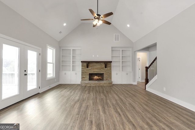 unfurnished living room featuring a fireplace, french doors, hardwood / wood-style flooring, and built in shelves