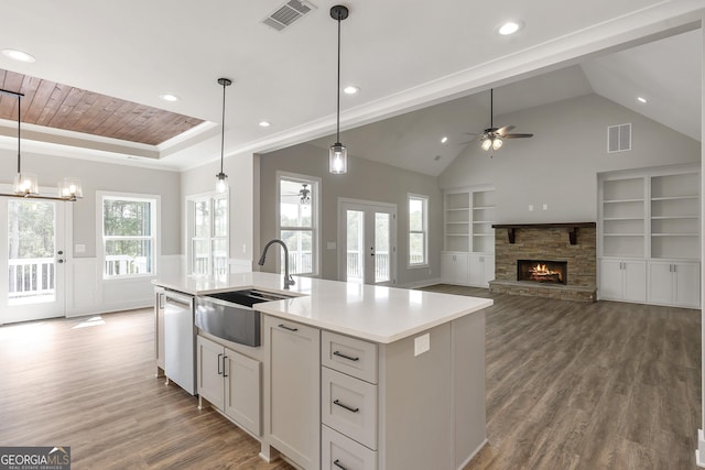 kitchen with sink, stainless steel dishwasher, an island with sink, and pendant lighting