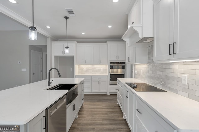 kitchen with sink, pendant lighting, stainless steel appliances, white cabinets, and an island with sink