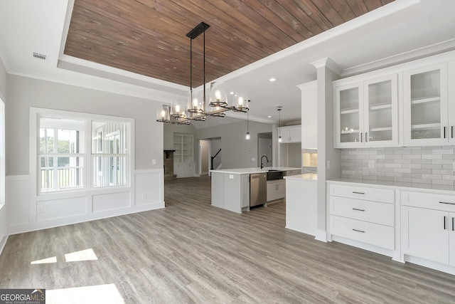 kitchen featuring hanging light fixtures, stainless steel dishwasher, a tray ceiling, white cabinetry, and a kitchen island with sink