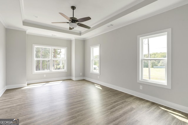 unfurnished room featuring hardwood / wood-style flooring, ornamental molding, a raised ceiling, and ceiling fan