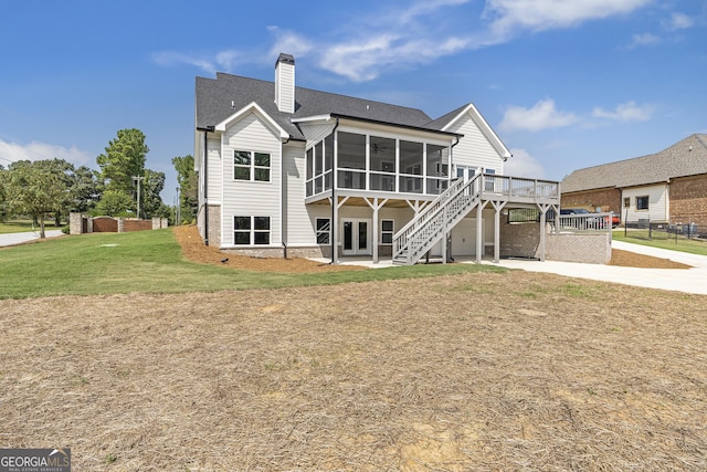 rear view of house with a lawn, a deck, and a sunroom