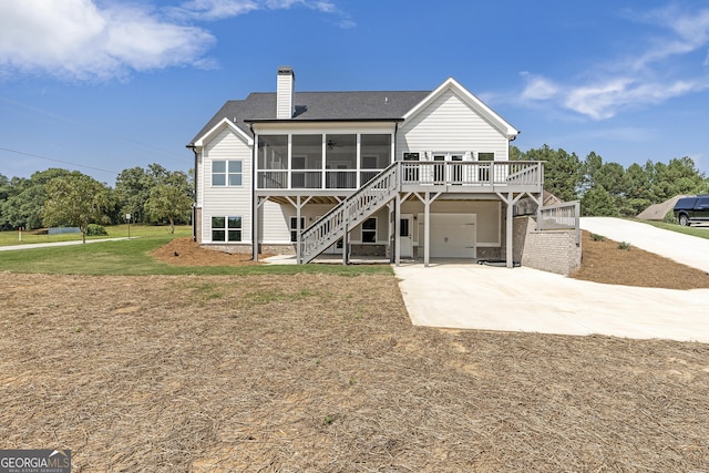 rear view of house with a lawn, a garage, and a sunroom