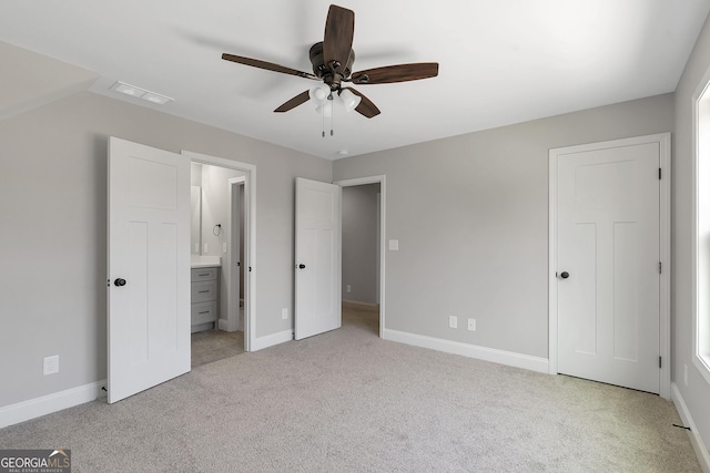 unfurnished bedroom with ceiling fan, ensuite bath, and light colored carpet