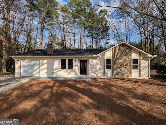 view of front of home featuring driveway, stone siding, a garage, and a chimney