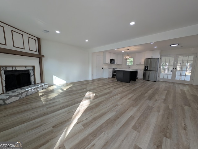 unfurnished living room with visible vents, a high end fireplace, french doors, light wood-type flooring, and recessed lighting