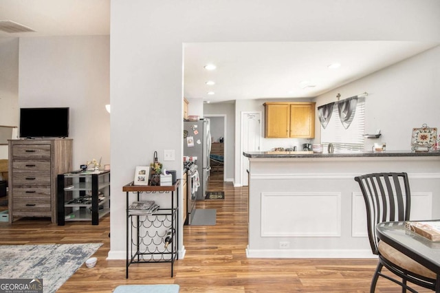 kitchen featuring light wood-type flooring, stainless steel refrigerator, and light brown cabinets