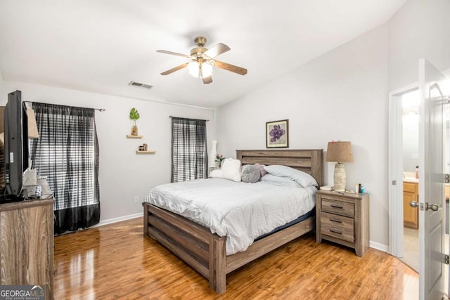 bedroom with lofted ceiling, ensuite bathroom, ceiling fan, and light hardwood / wood-style flooring