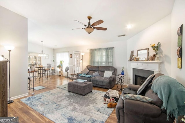 living room with ceiling fan with notable chandelier and light hardwood / wood-style flooring