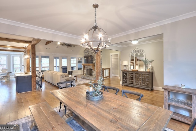 dining room with a fireplace, ornamental molding, a chandelier, and wood-type flooring