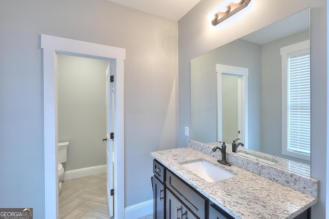 bathroom featuring parquet flooring, vanity, and toilet