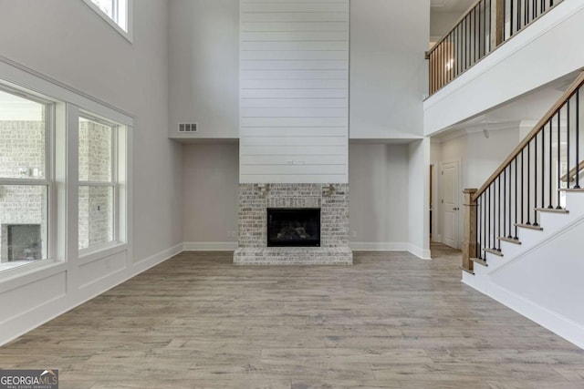 unfurnished living room with light hardwood / wood-style flooring, a high ceiling, and a fireplace