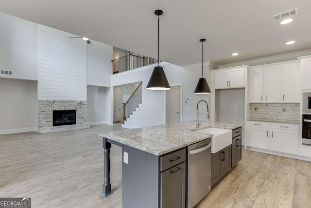 kitchen with stainless steel dishwasher, hanging light fixtures, and white cabinets