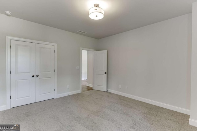 unfurnished bedroom with light carpet and a closet