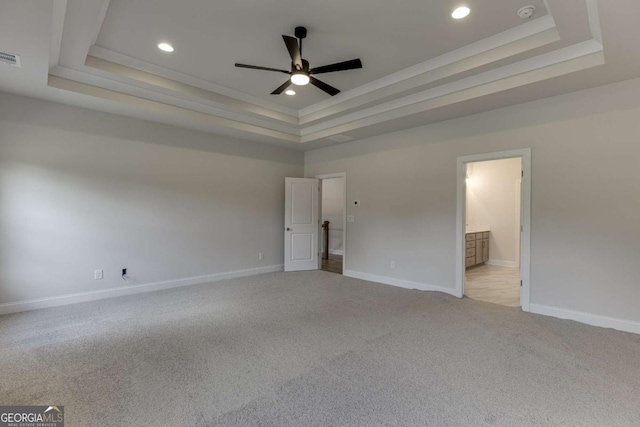 unfurnished bedroom with ensuite bathroom, crown molding, a tray ceiling, and light colored carpet