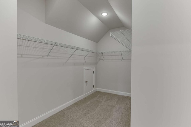 spacious closet with lofted ceiling and light colored carpet