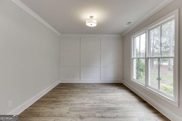 empty room featuring light wood-type flooring and ornamental molding